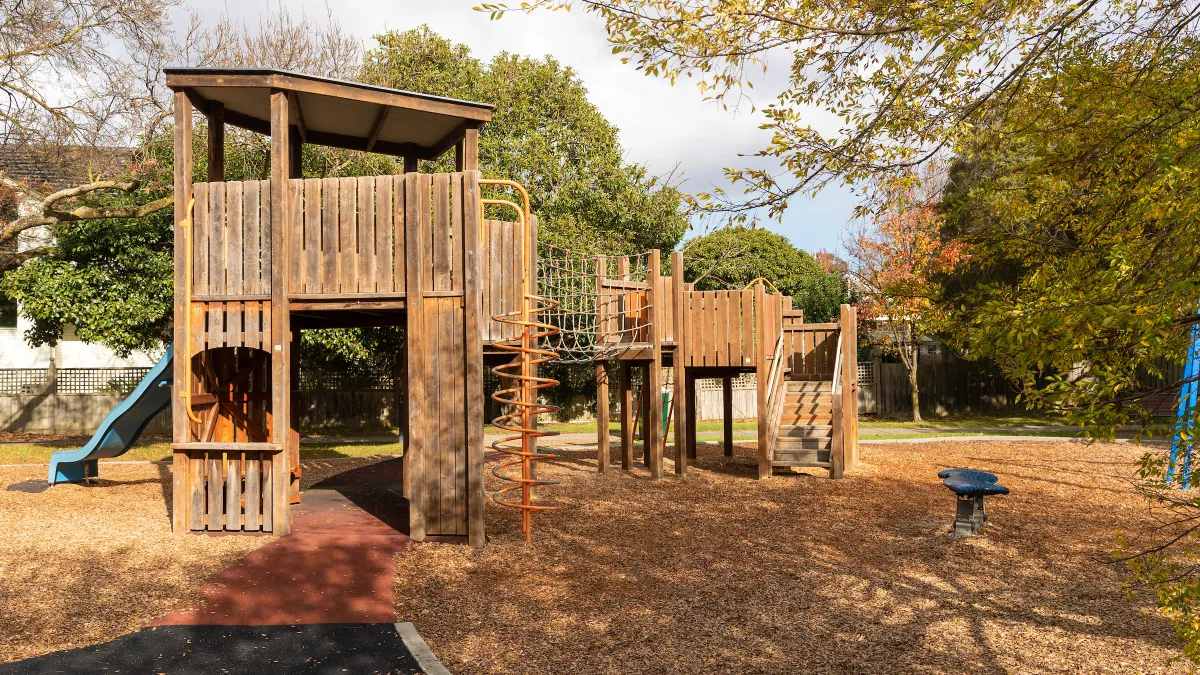 A wooden playground including a slide and a path through the playground