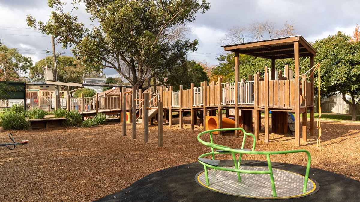 A wooden playground including a accessible merry-go-round