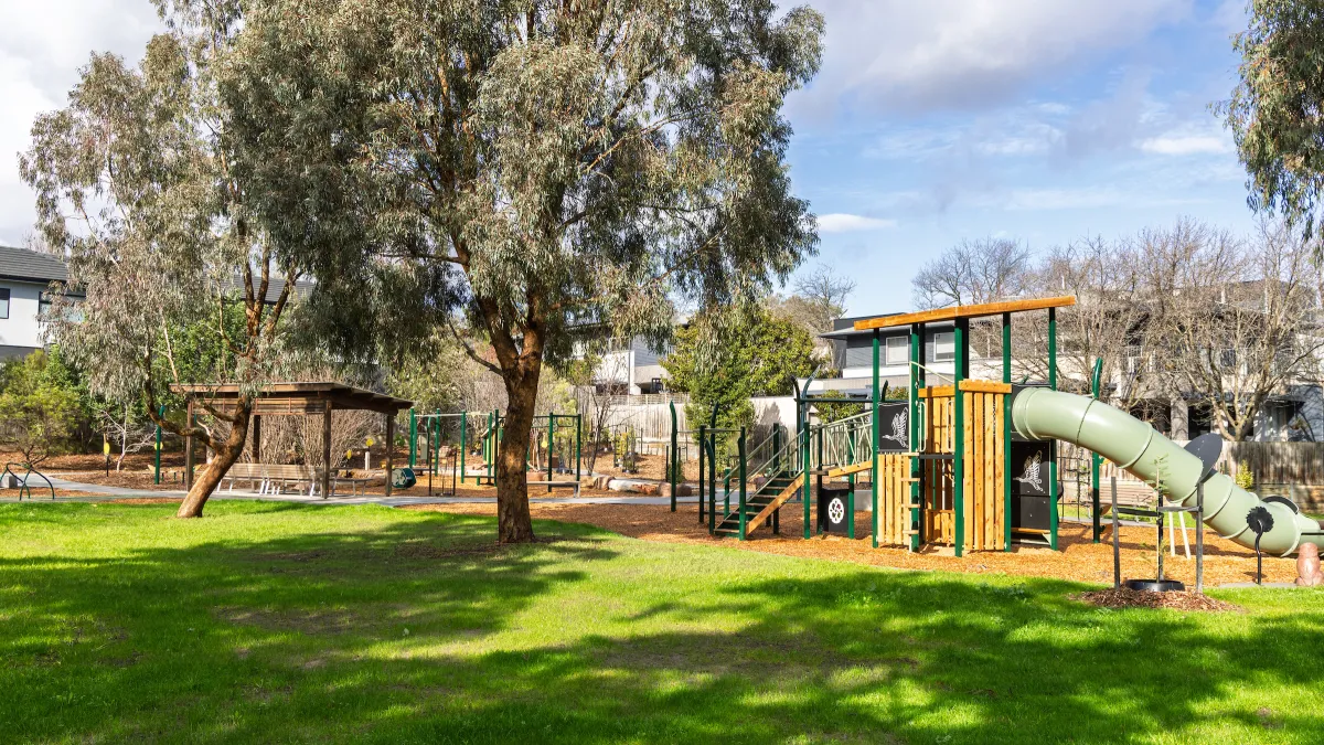 A playground surrounded by trees and green lawn
