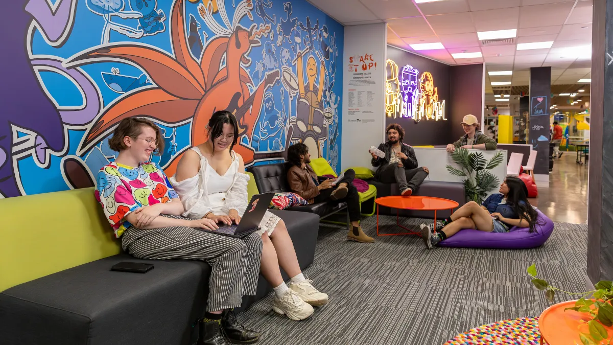 A group of young people sit in a colourful office space.