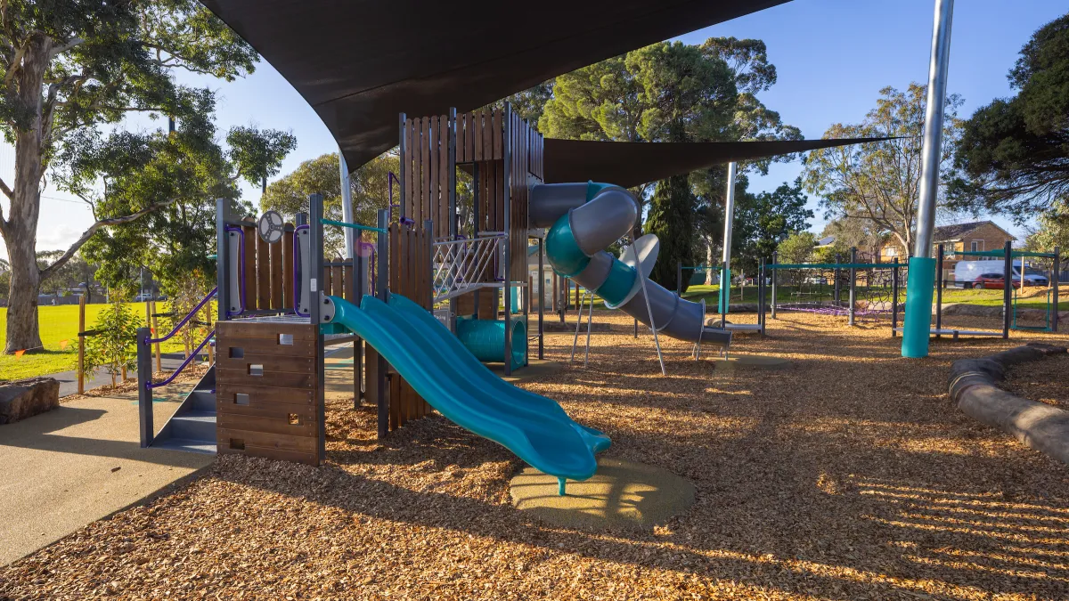 A small slippery dip and a larger covered slide in a playground