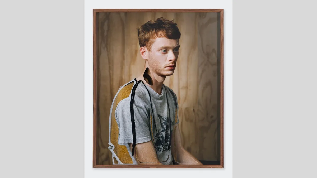 A collaged portrait of a person with short red hair wearing a tshirt, in front of a wooden veneer background 