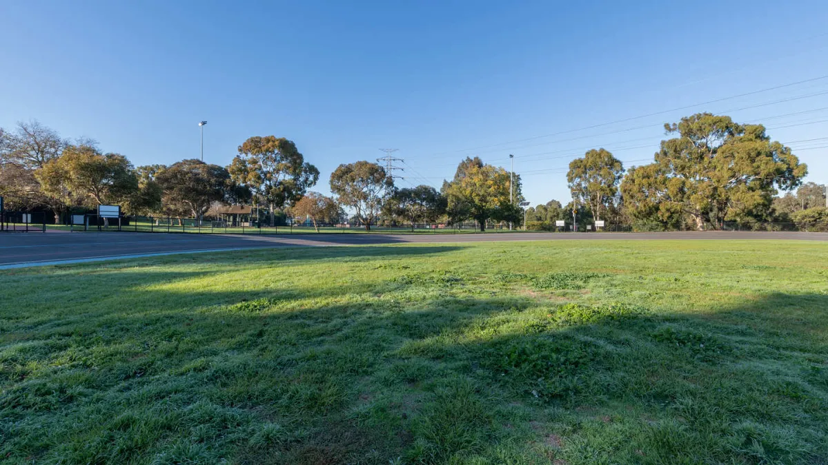 A field of grass. In the background is a lined running/cycling track 