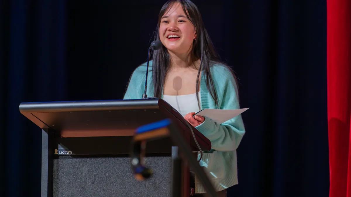 A young woman stands behind a lectern looking very excited