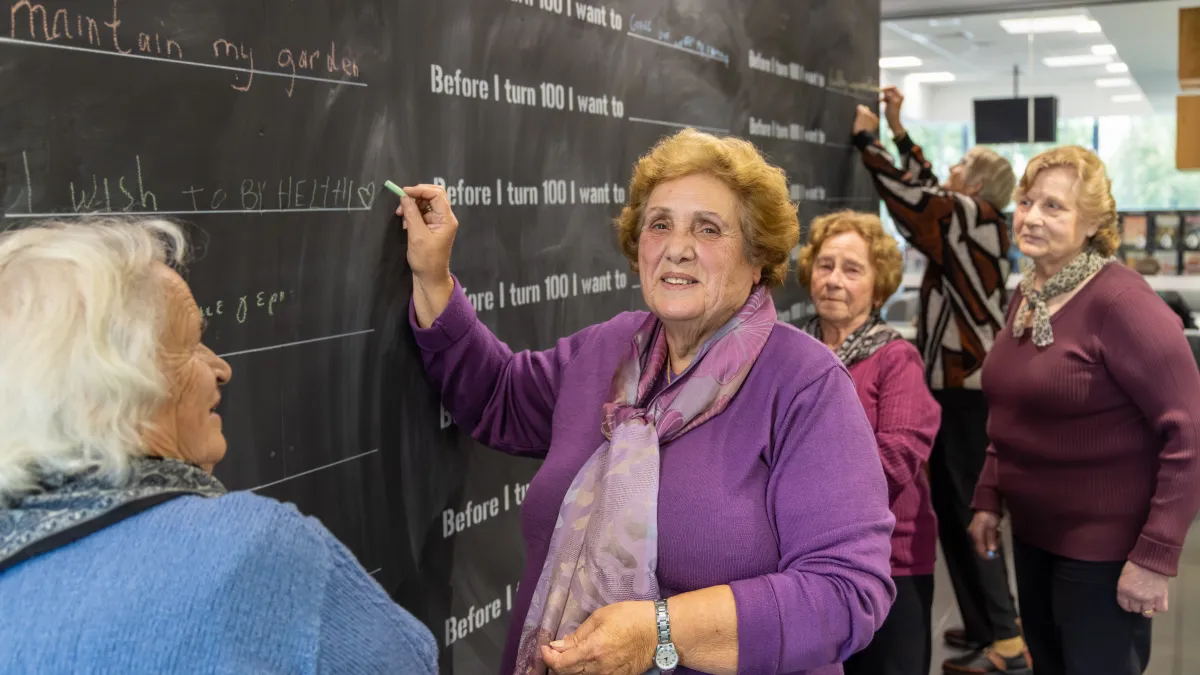 Four women over 60 write on a blackboard