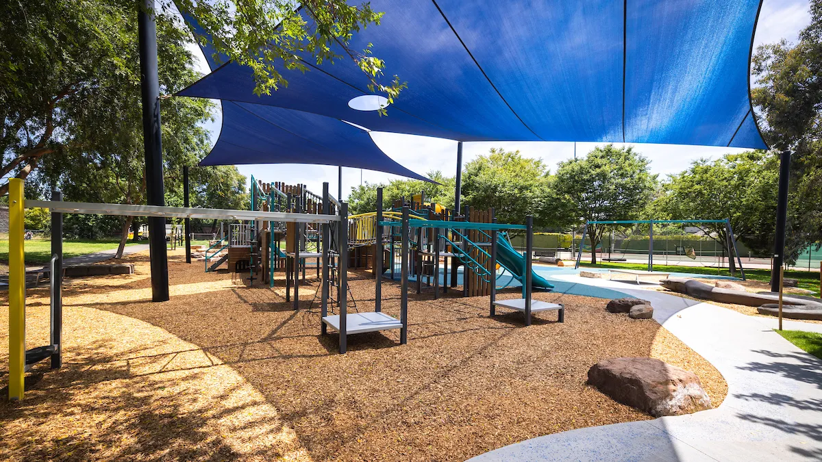 a small and compact playground is screened by blue shadecloth