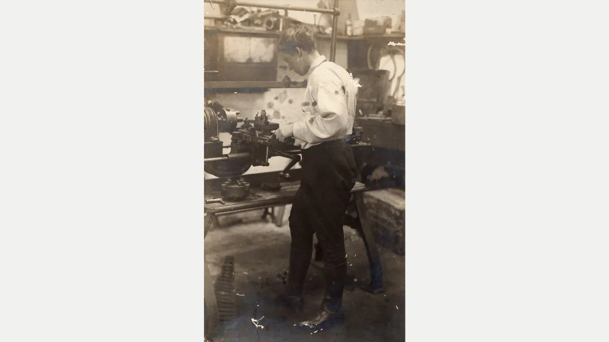 A woman in a white shirt and black pants working at a lathe