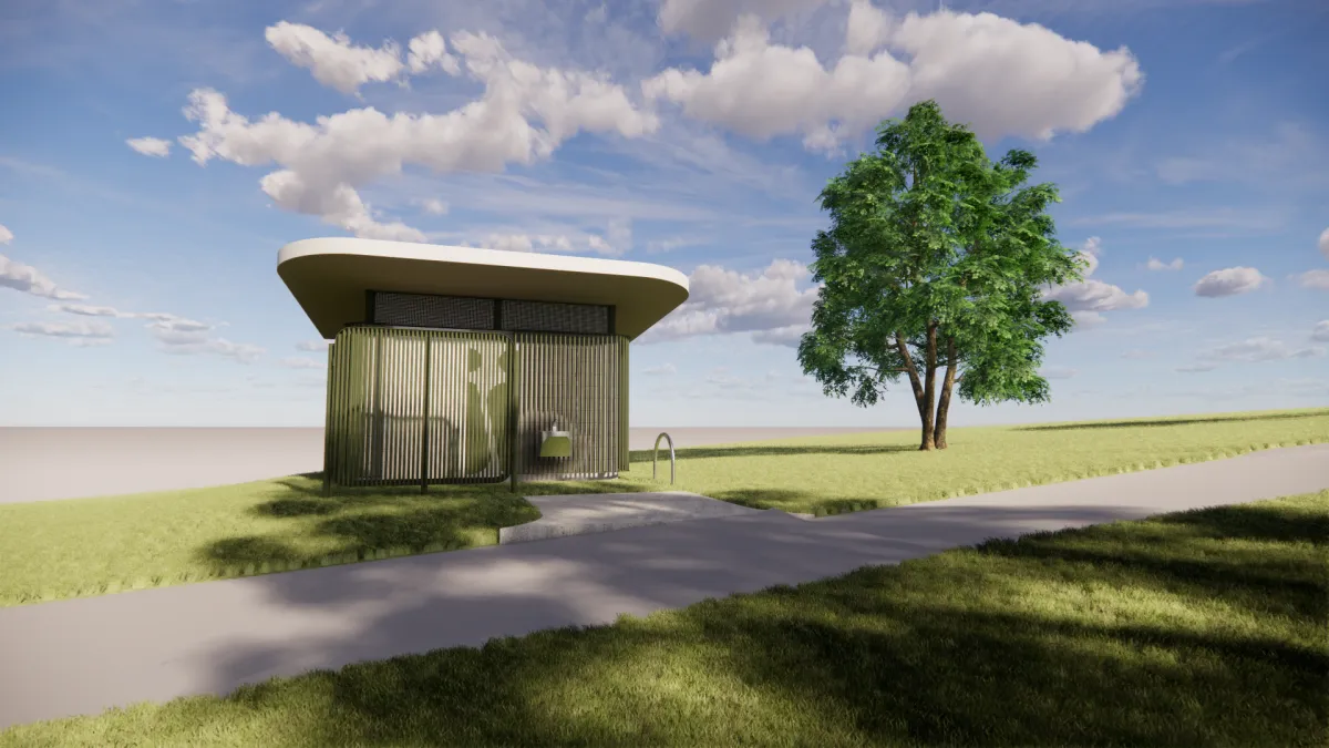 The front of a toilet block. It is next to a footpath and a single tree. the toilet is green and cream to help it blend into the surroundings.