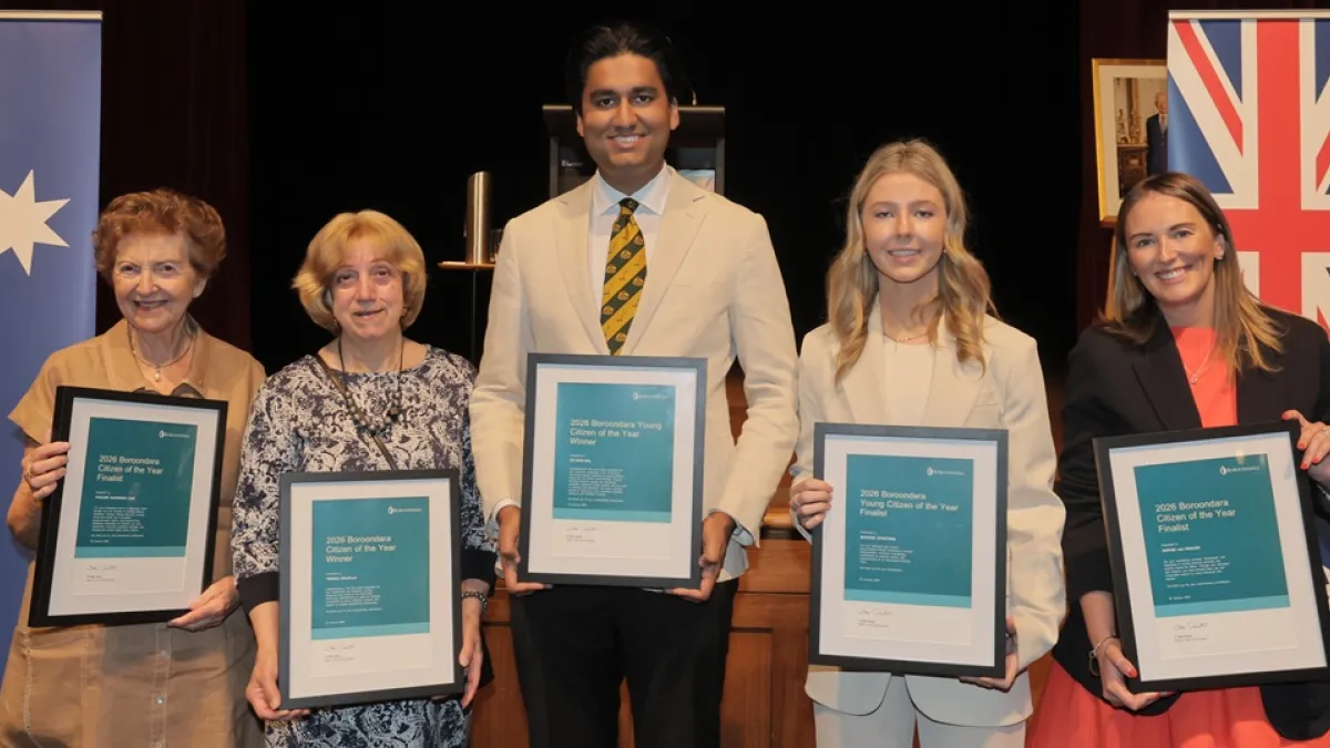 Five people holding citizen of the year awards standing together on a stage