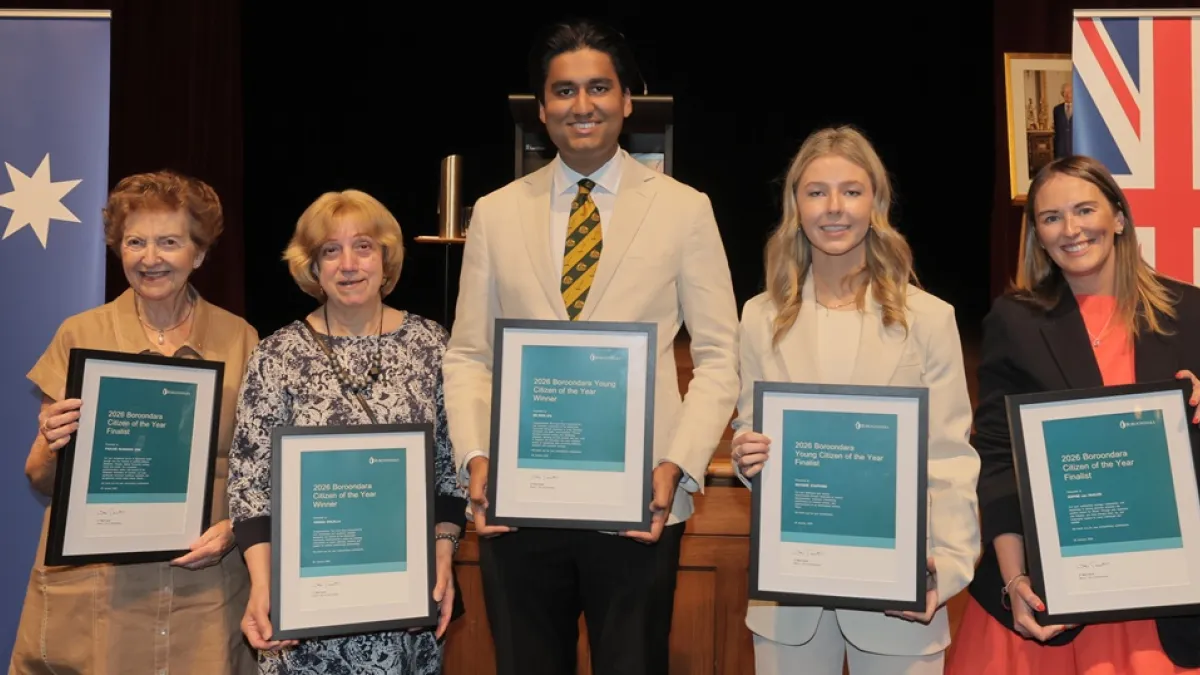 Five people holding citizen of the year awards standing together on a stage