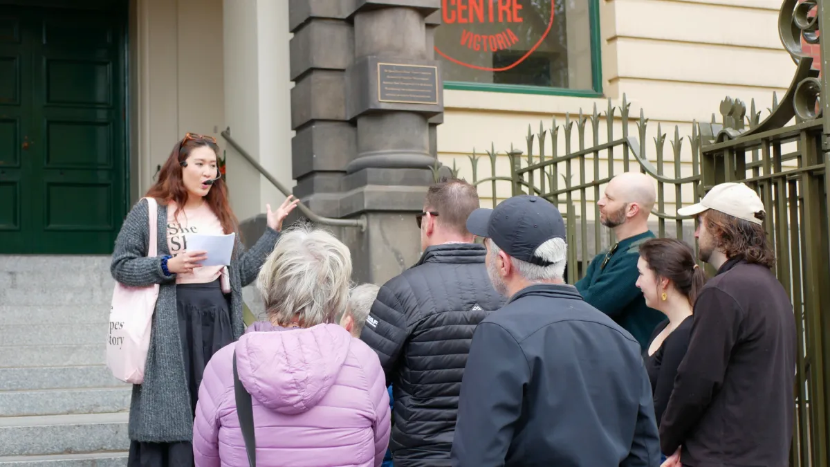 A woman speaks to a group of people in front of the Queen Victoria Women’s Centre.
