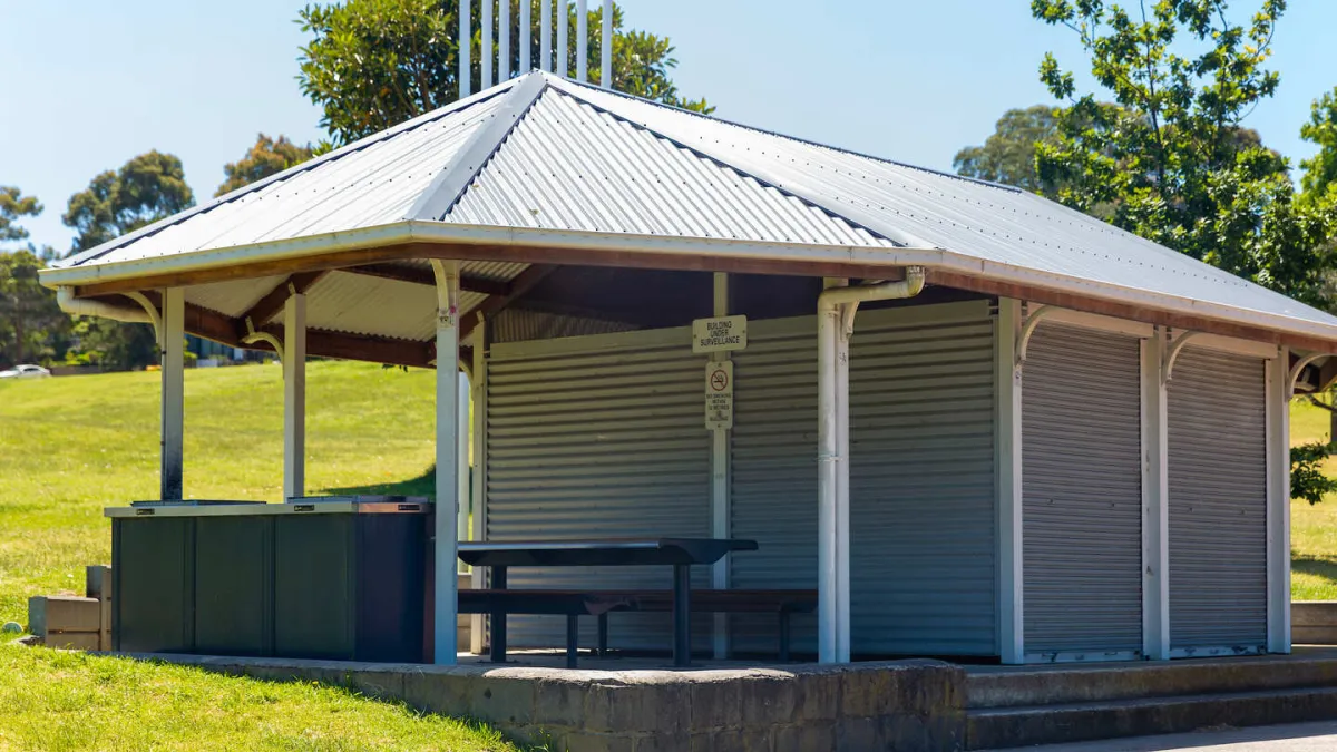A small building with an undercover patio featuring a picnic table and barbecue. 