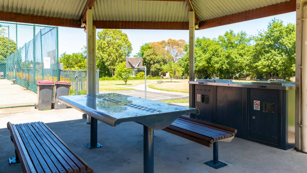 An undercover seating area featuring a picnic table and 2 burner barbecue