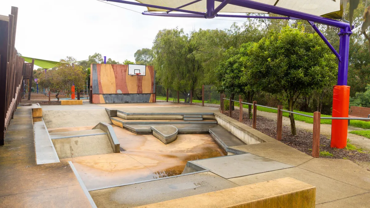 A skate park with a basketball hoop in the background