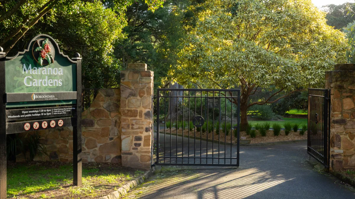 The iron gates are open to Maranoa Gardens on a sunny late afternoon