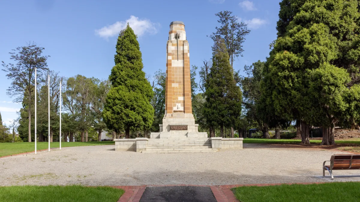 Front view of the restored St James Park war memorial with 3 flag poles and seating.