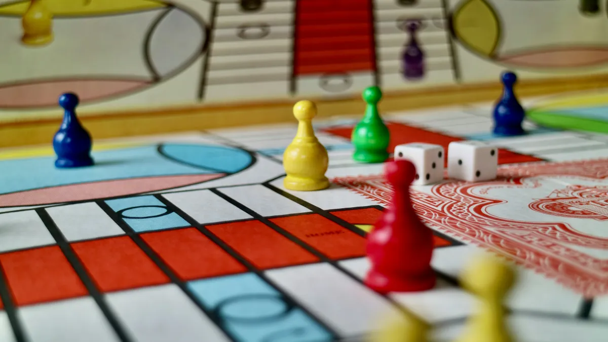 Colourful game pieces and a dice sit on a board game.
