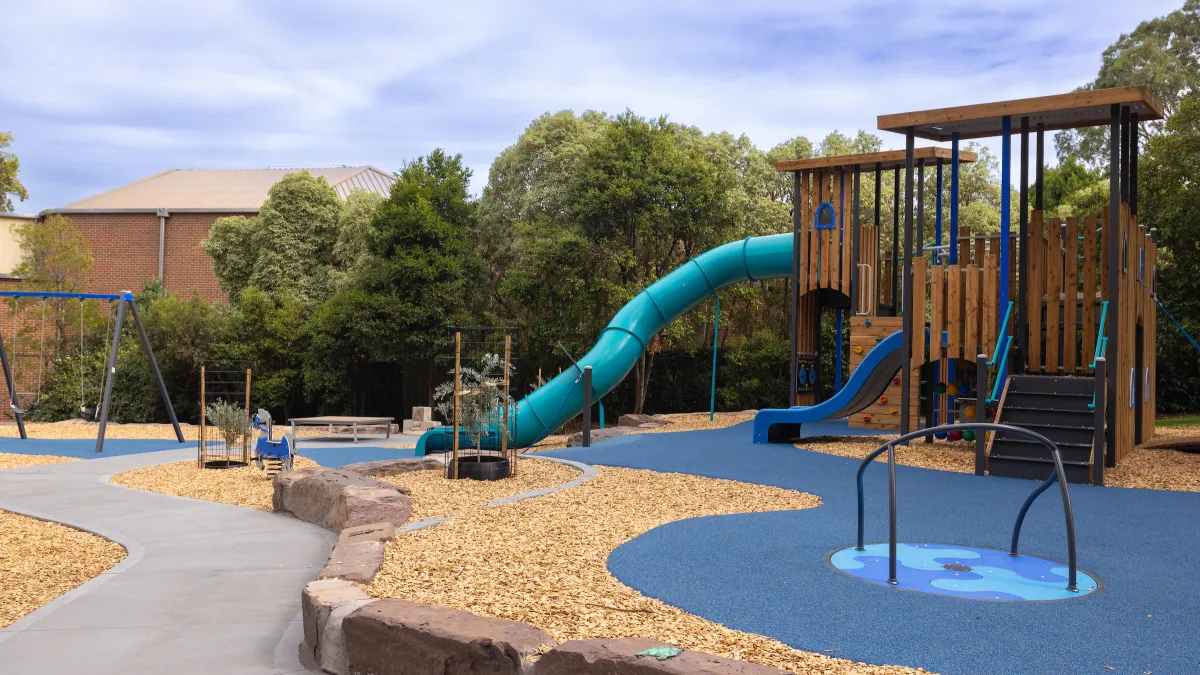A small playground with a timber play unit, enclosed slide and balancing unit 