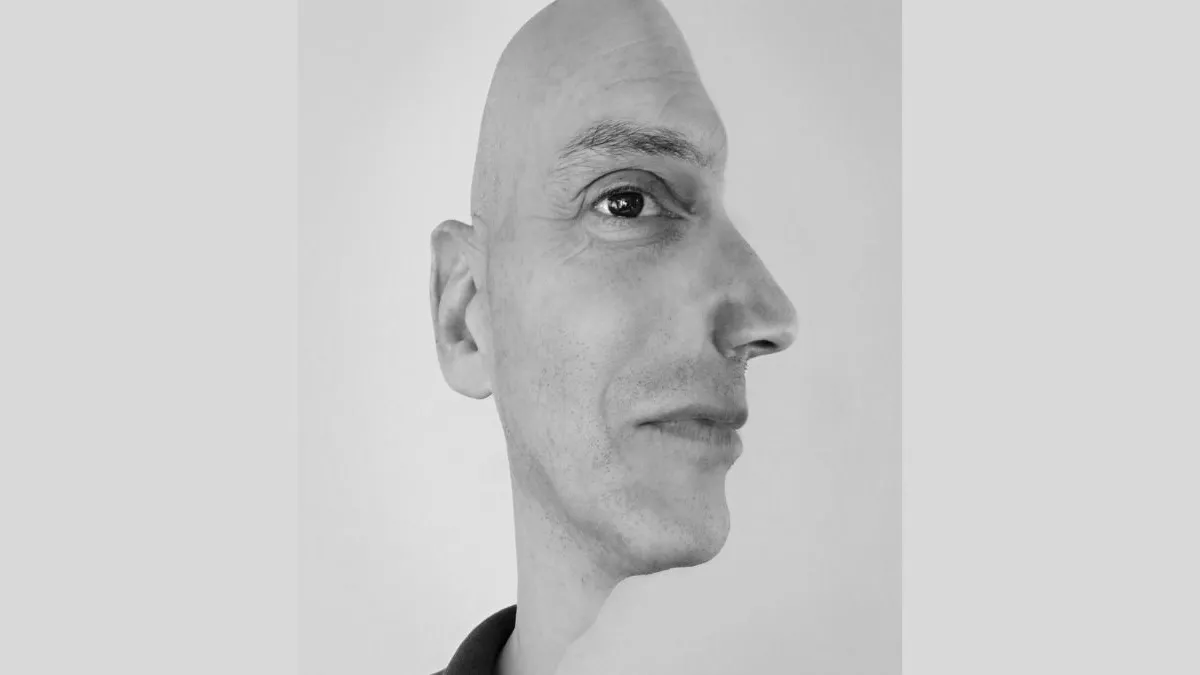 Image of two black-and-white photographs that have been digitally blended into one image. Both photos are of a single person with a shaved head, one taken from the front and the other from their side. The outline of the right-hand side of the figure features the outline of the figure's face and nose from their side, and the left-hand side shows the outline of the right-hand side of their head and ear. The photos are blended, so the figure has one visible eye staring forward and half a mouth.