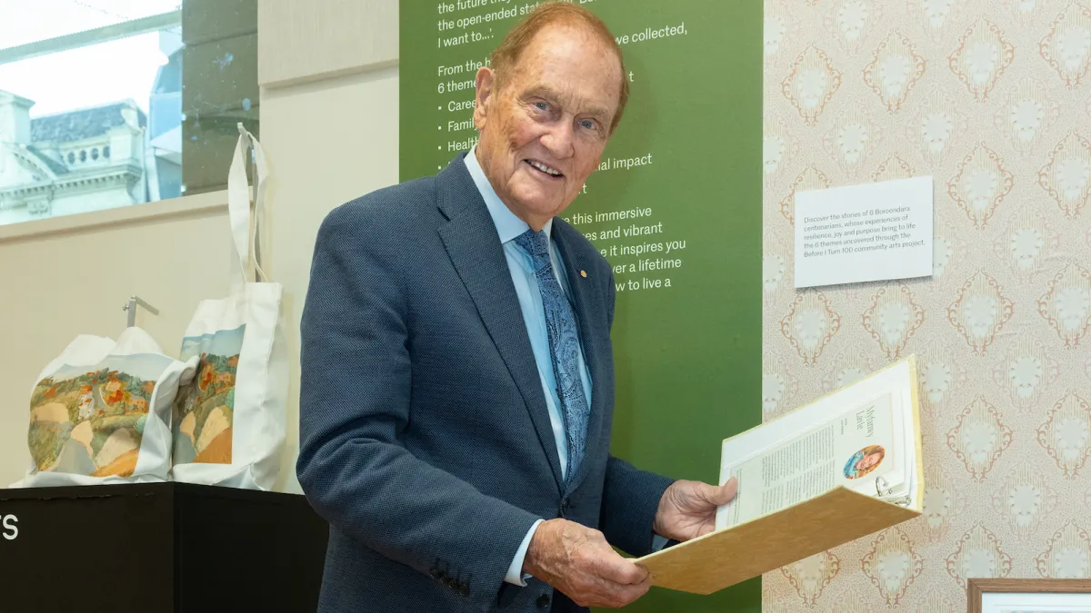 An older man wearing a suit holds a book.