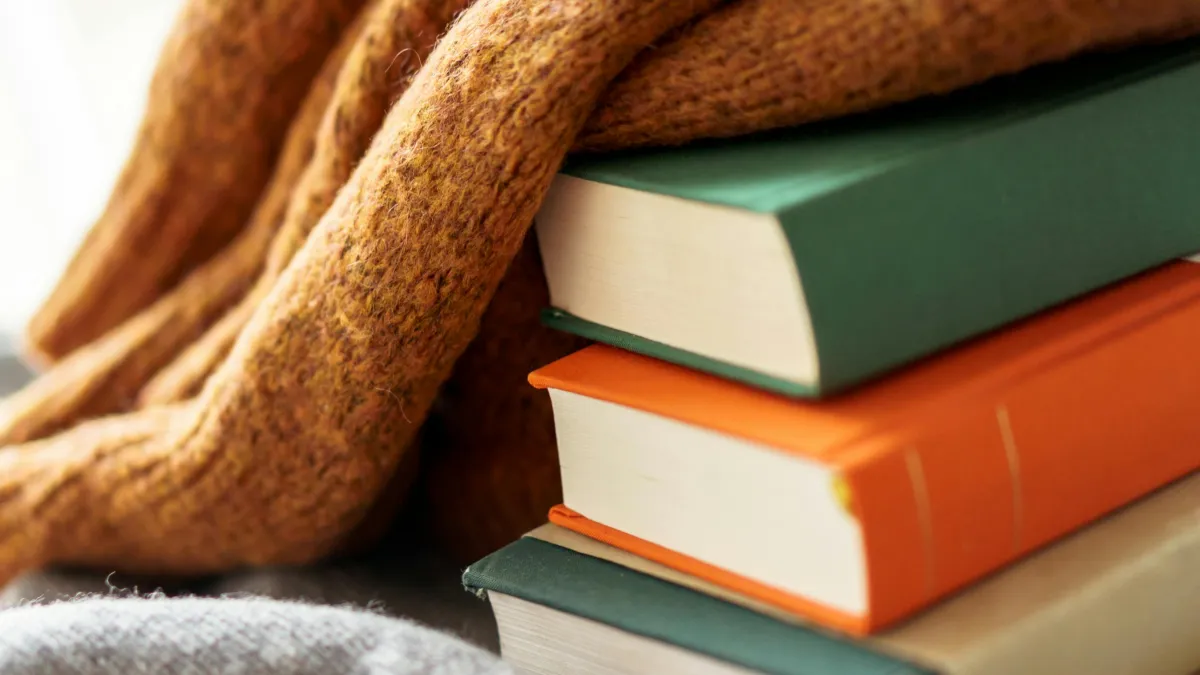 Close up photo of stack of books with a blanket on top