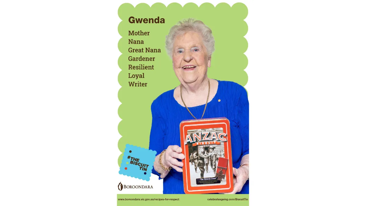 Gwenda wears a bright bule top. Her biscuit tin says 'ANZAC biscuit' and has a photo of soldiers on it.