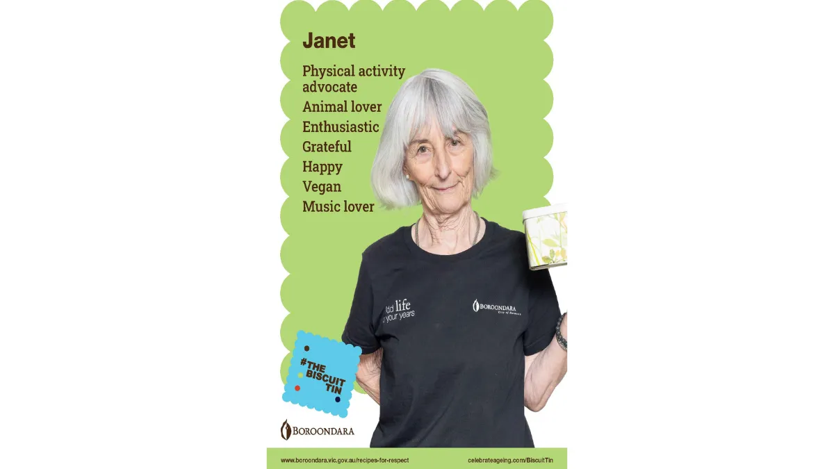 Janet wears a black tshirt and has short grey hair cut in a bob. Her biscuit tin is white with green leaves along the side.
