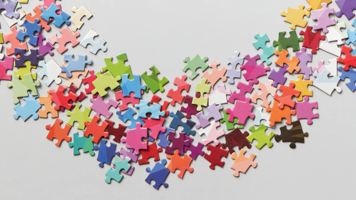 Colourful puzzle pieces are scattered on a grey background