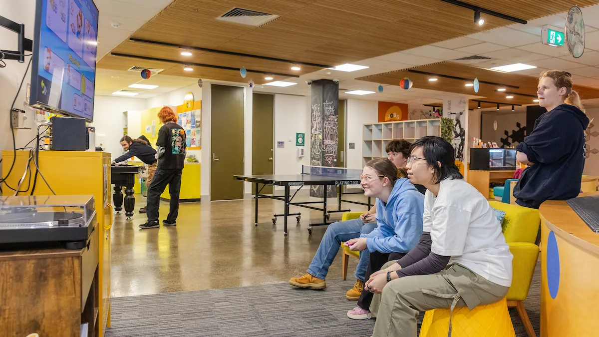 A goup of young people playing video games in the youth hub.