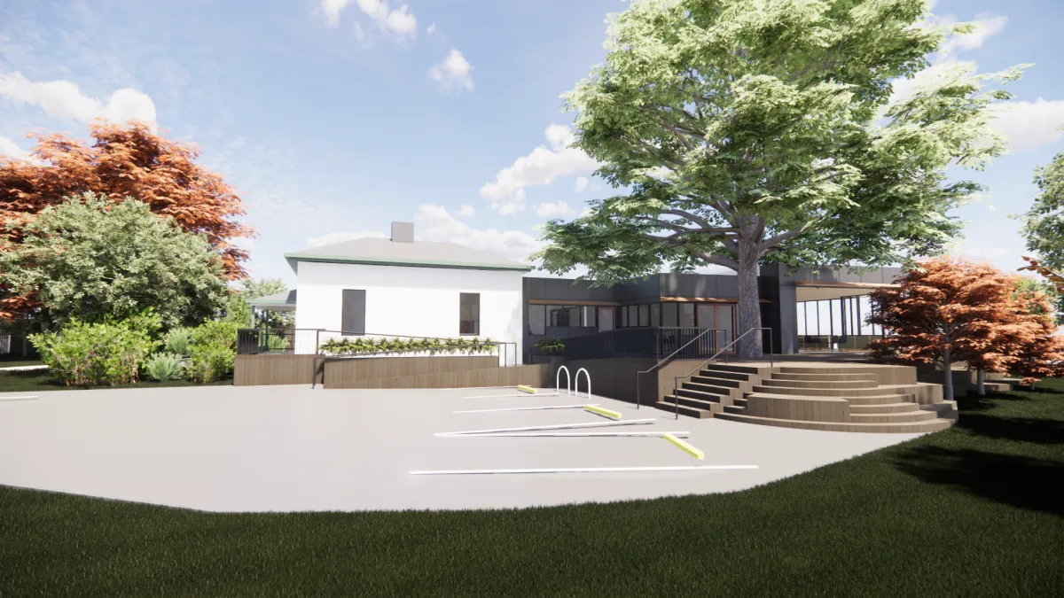 Stairs and a ramp leading from a carpary to a tree surrounded building. the building has lots of large windows.