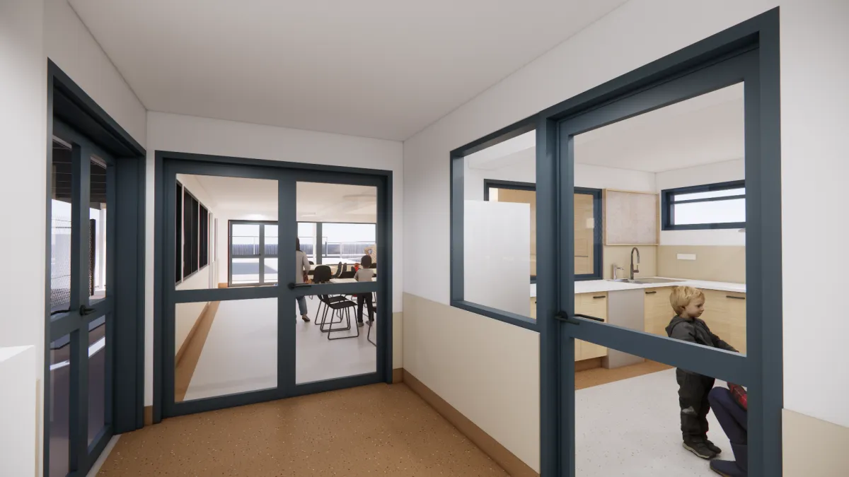 Entry space to the building. to the right is a glass door through which a kitchen can be seen. To the left is another glass door that is at such an angle that we can't see into the room. Straight ahead is a glass door into a larfe, light filled space. On the far side are doors leading to outside. in the Room chairs and tables are set up.