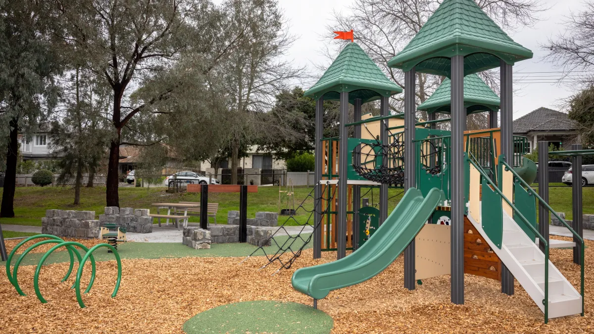 A play unit with 2 slides in a tree-ringed playground