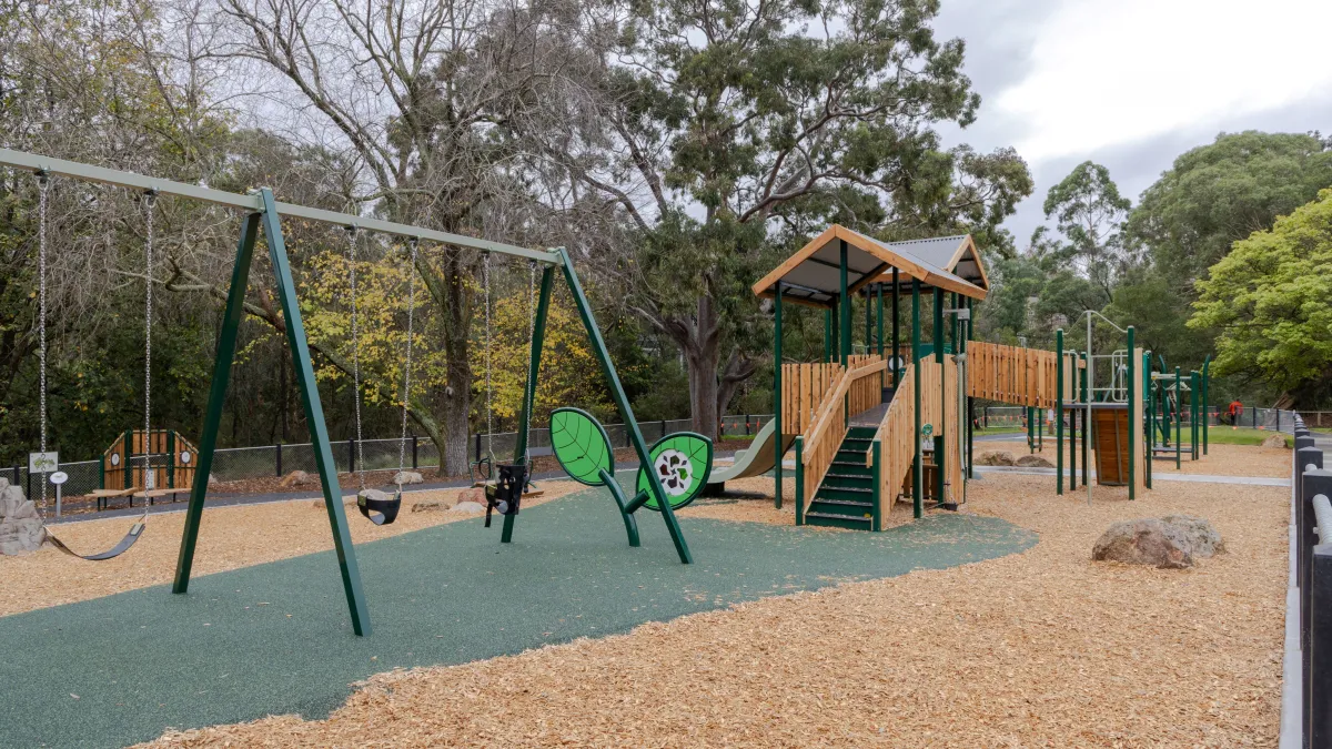 Three swings and a timber climbing unit at a playground