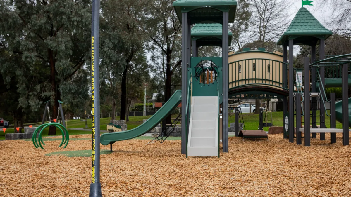 A castle-themed play unit with turrets and bridge in a playground