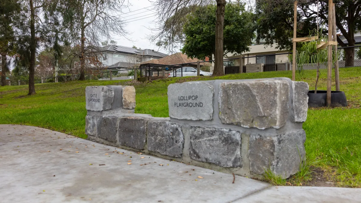 A short bluestone wall in which is inscribed the words 'lollipop playground'