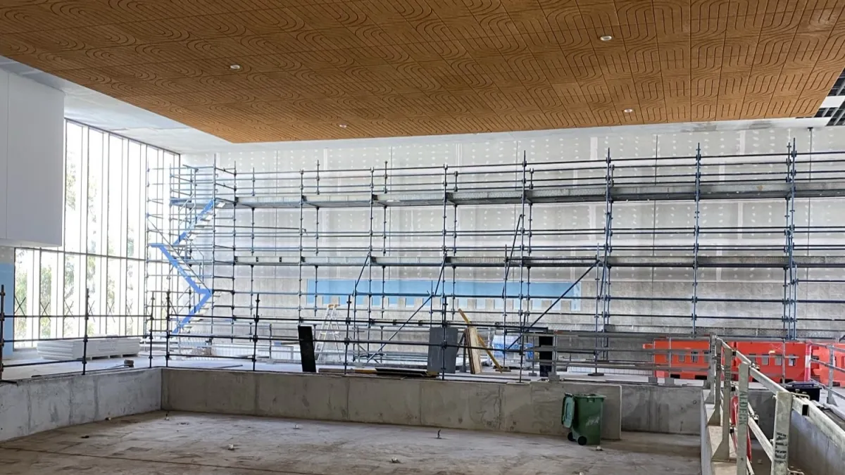 An underconstruction space with wooden ceiling and scaffolding on the walls. 