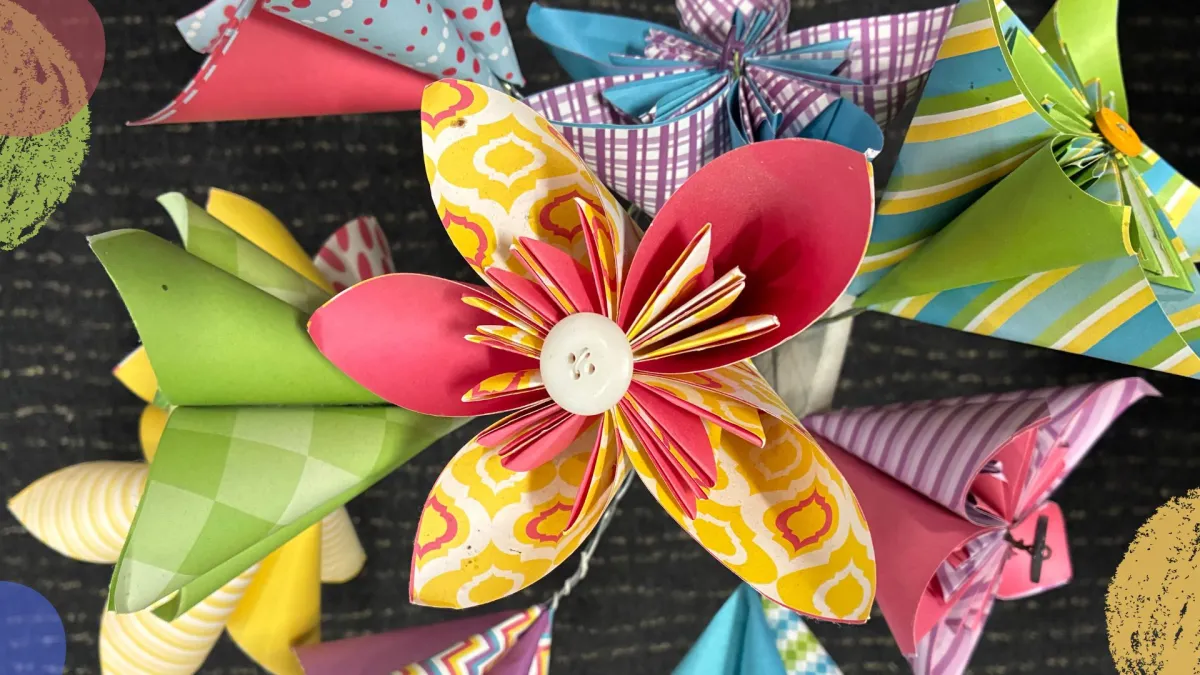 A bunch of brightly coloured origami flowers sit on a black background