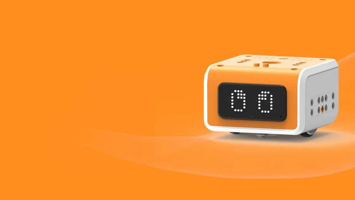 A square orange and white robot with wheels sits on an orange background