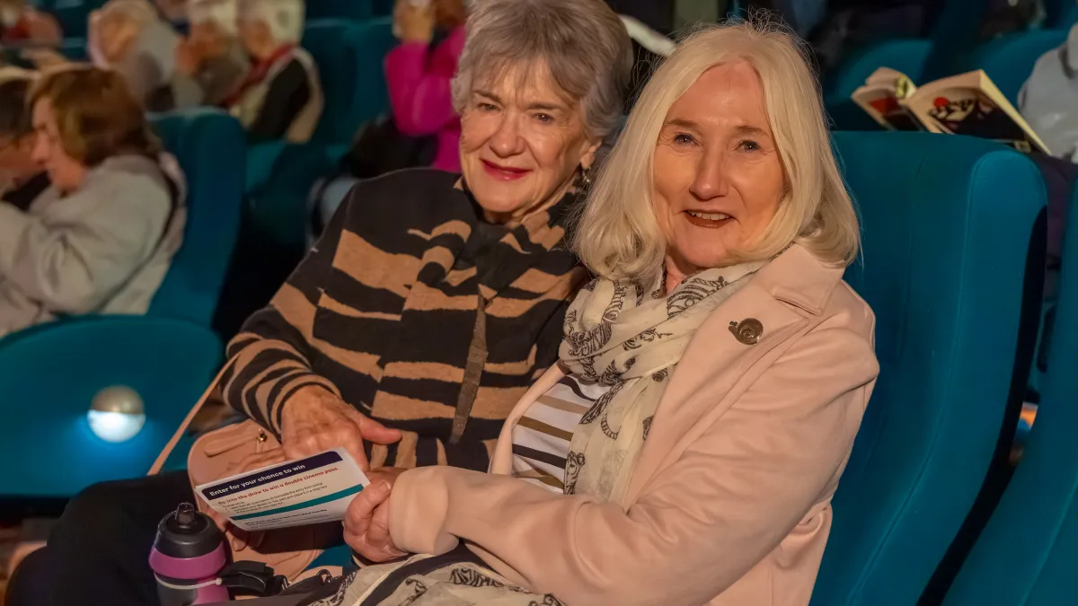 Two senior women sitting together in a cinema.