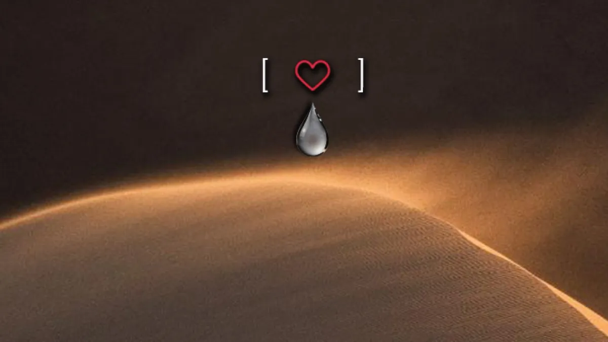 A sand dune with the top blowing in the wind. A heart and a teardrop are placed above the dune