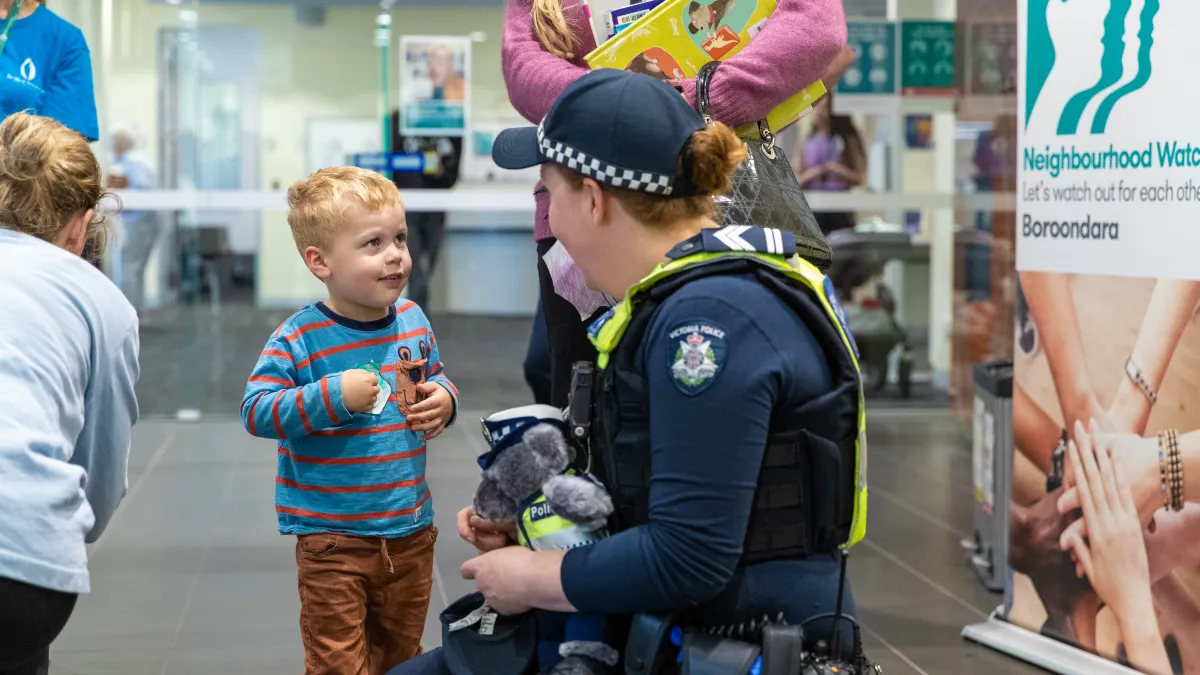 A child talks to a police officer kneeling towards them