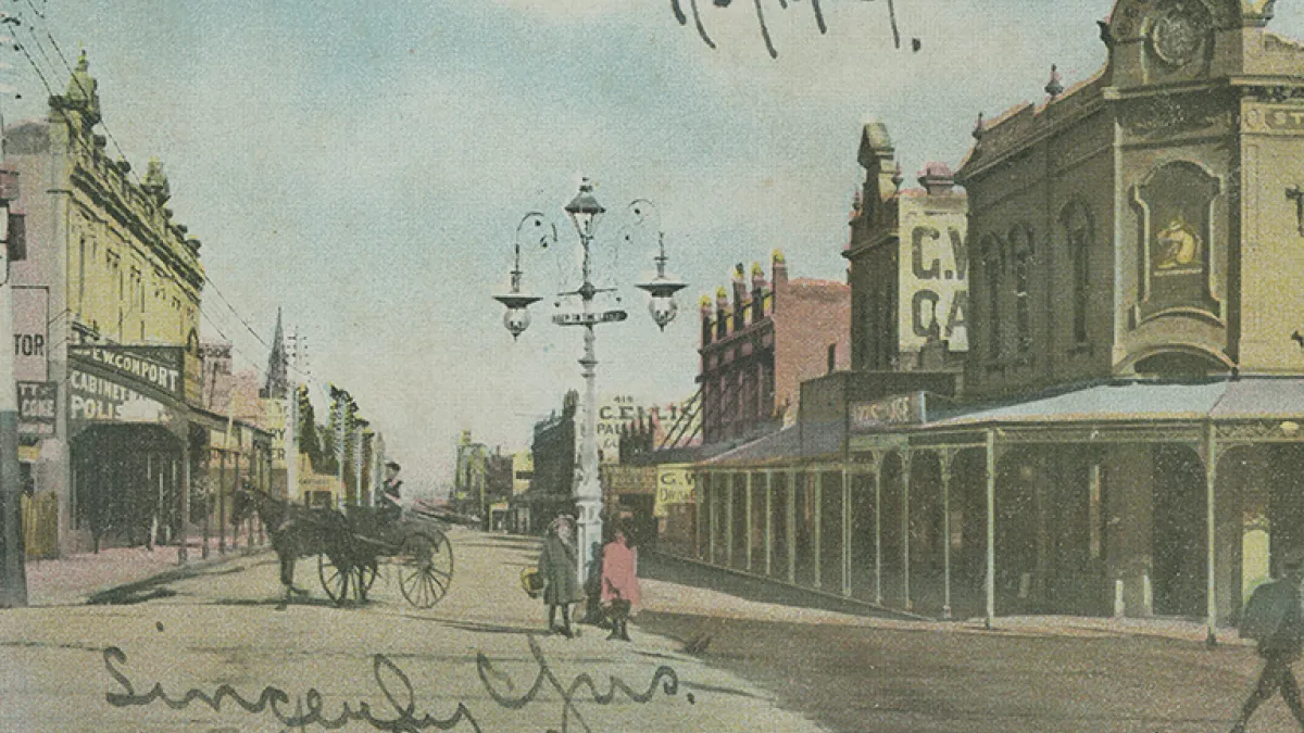 Old image of historical buildings and a horse and cart being ridden down a street