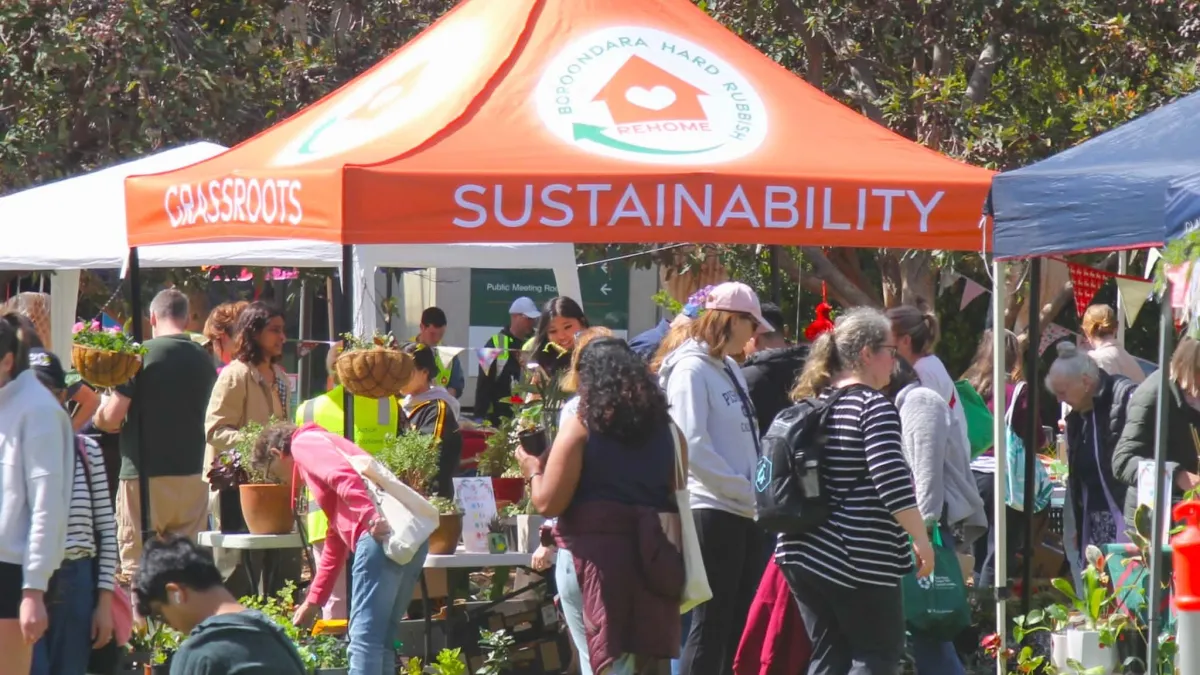 A busy market. A stall is covered with tent that has "sustainability" on the side.