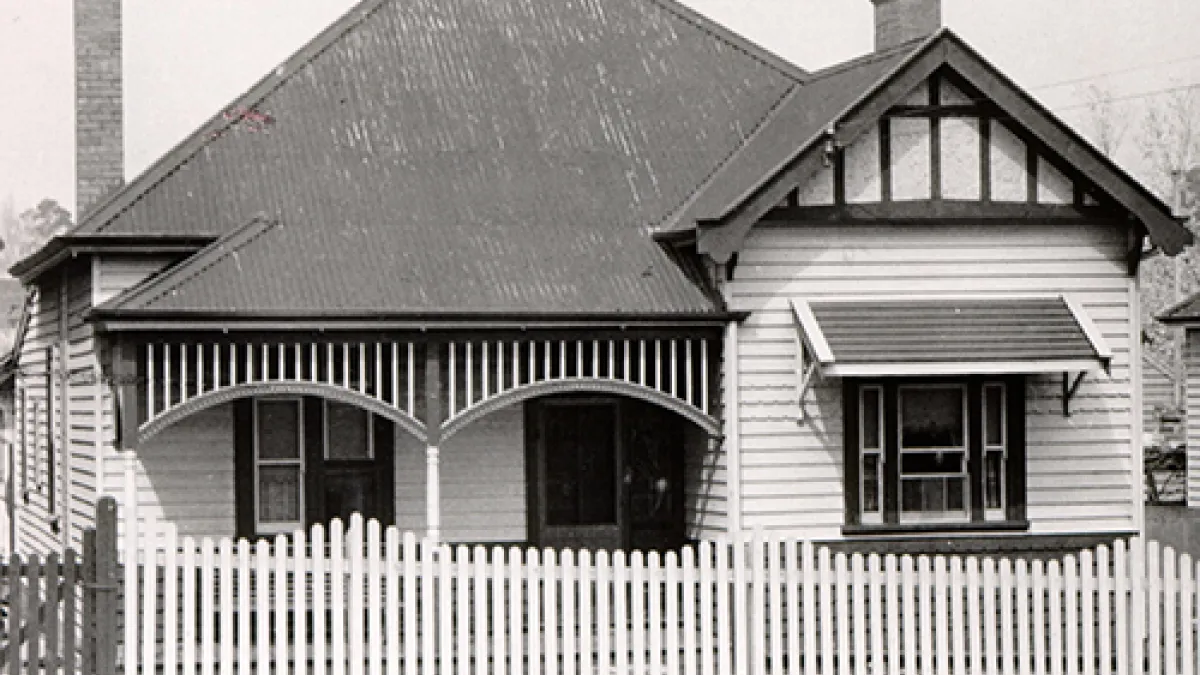 Black and white image of timber house with small timber fence out the front