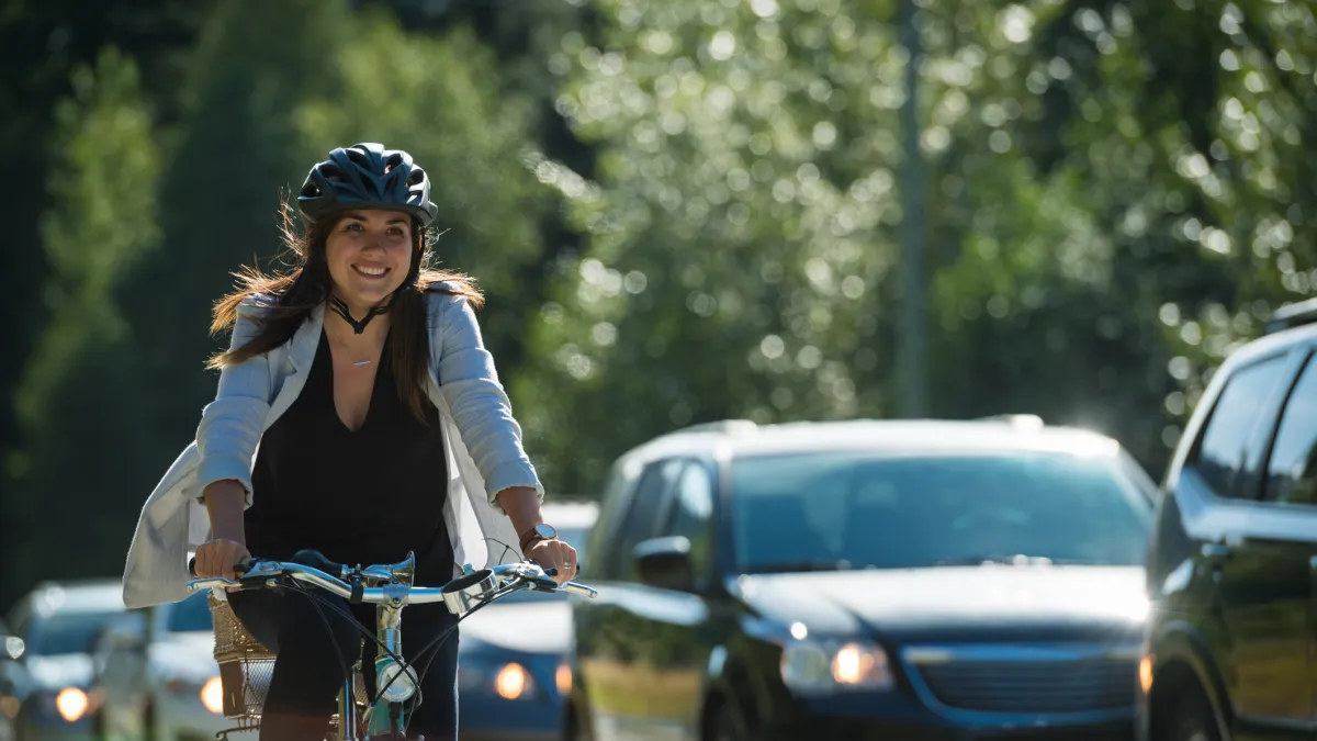 A woman rides a bike past a line of cars on the road.