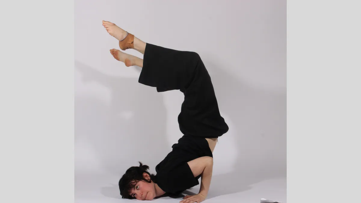 Photograph of a dancer pushing themselves up from the floor with their legs in the air