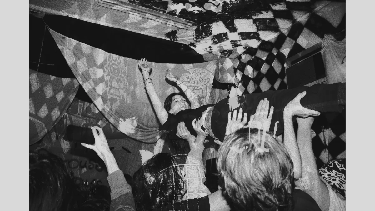 Black and white photograph of someone crowd surfing