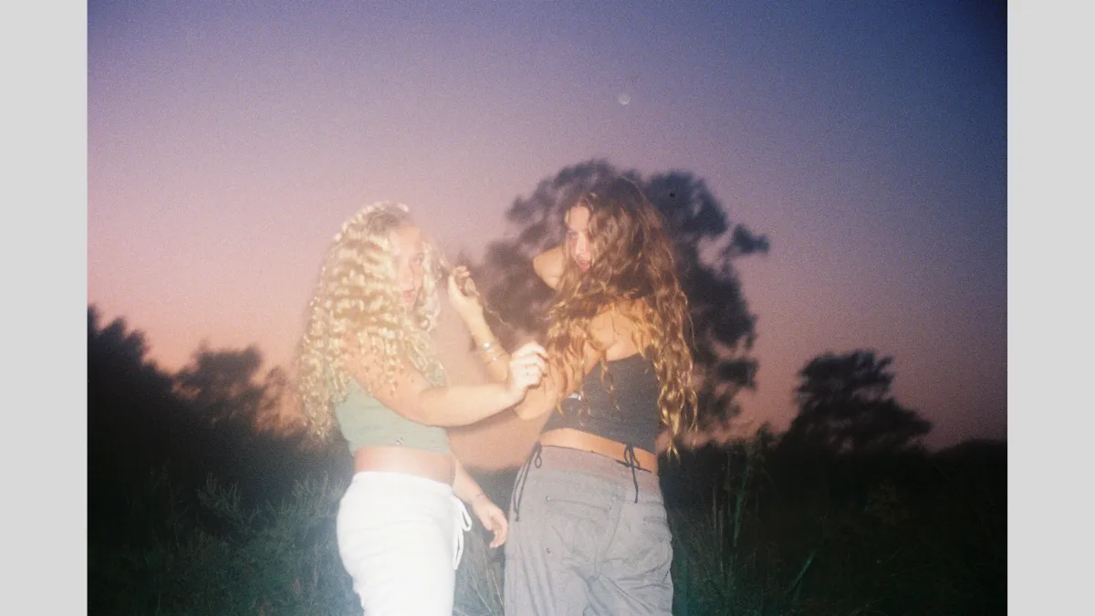 Photograph of two girls playing with each other's hair