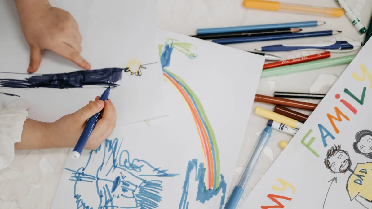 Child drawing with many coloured pencils