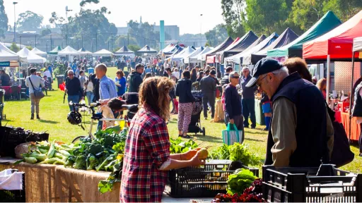 Shoppers browsing a row of stalls at an outdoor farmers market